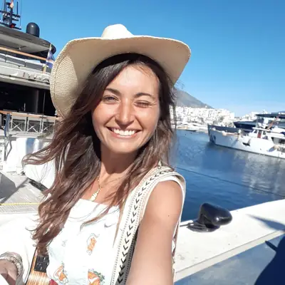 Leyla lacht mit Strohhut am Hafen