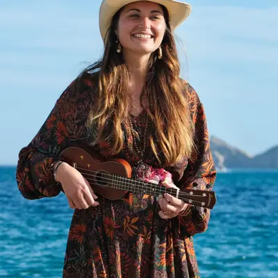 Leyla mit Strohhut und Ukulele vor dem Meer