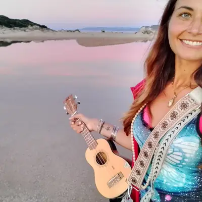Leyla mit Ukulele an einem rosa schimmernden Strand
