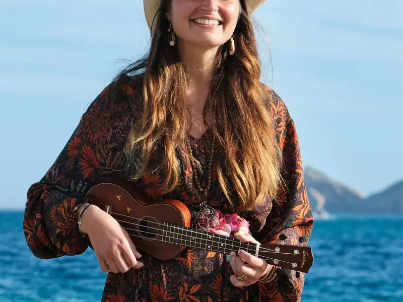 Leyla mit Strohhut und Ukulele vor dem Meer